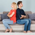 Unhappy Couple With Arms Crossed Sitting On Sofa
